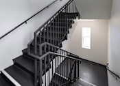 Thumbnail 28 of 94 - A staircase with a metal railing and black steps.