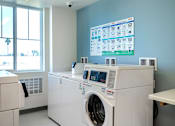 Thumbnail 26 of 94 - A large washing machine is in a room with a monitor on the wall.