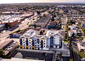 Thumbnail 9 of 94 - A large white building with a yellow stripe is in the center of a parking lot.