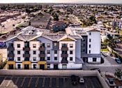 Thumbnail 13 of 94 - A large white and yellow building with a parking lot in front.