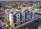 Thumbnail 8 of 94 - A large apartment complex with a parking lot in front.