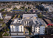 Thumbnail 7 of 94 - A large white building with a black roof is surrounded by a parking lot.
