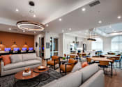 Thumbnail 85 of 90 - A modern living room with a grey sofa, orange pillows, and a coffee table.