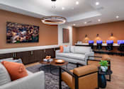 Thumbnail 82 of 90 - A modern living room with a grey sofa, orange pillow, and a painting on the wall.
