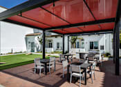 Thumbnail 75 of 90 - A patio with a table and chairs under a red canopy.