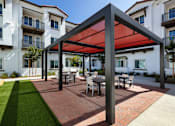 Thumbnail 79 of 90 - A patio with a table and chairs under a red canopy.