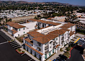 Thumbnail 61 of 90 - A large white building with a red roof is surrounded by a parking lot.