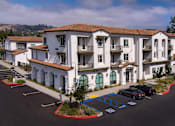 Thumbnail 68 of 90 - A parking lot in front of a white apartment building.