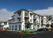 Thumbnail 72 of 90 - A row of white buildings with balconies and green doors.