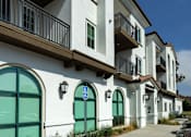 Thumbnail 67 of 90 - A row of apartment buildings with green doors and windows.