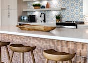 Thumbnail 65 of 90 - A kitchen with a white counter top and wooden stools.