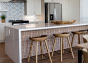 Thumbnail 74 of 90 - A kitchen with a white counter and wooden stools.