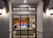 Thumbnail 66 of 90 - A modern house entrance with a glass door and a bench inside.