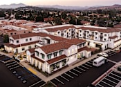 Thumbnail 32 of 90 - A parking lot in front of a white building with a red roof.
