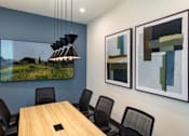 Thumbnail 59 of 90 - A conference room with a long table and chairs, a hanging light fixture, and two abstract paintings on the wall.