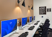 Thumbnail 36 of 90 - A row of computers are lined up on a white desk.