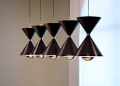 Thumbnail 45 of 90 - A group of black hanging lamps with a wooden table and chairs below.