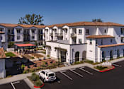 Thumbnail 21 of 90 - A white building with a red roof and a parking lot in front.