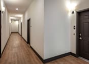 Thumbnail 15 of 90 - A long hallway with doors on both sides and lights on the ceiling.