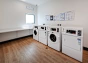 Thumbnail 14 of 90 - Three washing machines are lined up in a laundry room.