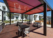 Thumbnail 8 of 90 - A patio with a table and chairs is covered by a red awning.
