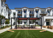 Thumbnail 20 of 90 - A white building with a red roof and a green lawn in front.