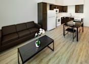 Thumbnail 9 of 90 - A brown couch sits in a living room with a ceiling fan and a dining table with chairs.