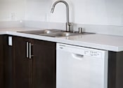 Thumbnail 11 of 90 - A white dishwasher is in a kitchen with dark brown cabinets.
