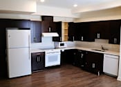 Thumbnail 14 of 25 - A kitchen with dark brown cabinets and white appliances.