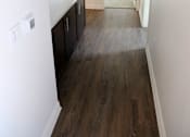 Thumbnail 22 of 25 - A long, narrow hallway with dark wood floors and white walls.