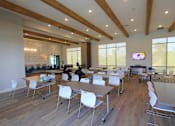 Thumbnail 3 of 25 - A conference room with a long table and chairs, a television on the wall, and a view of the outdoors through the windows.