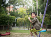 Thumbnail 20 of 21 - A young boy is swinging on a swing in a park.