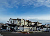 Thumbnail 19 of 61 - A parking lot with cars and a building in the background.