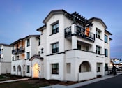 Thumbnail 24 of 61 - A modern white two-story building with balconies and arched windows.