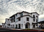 Thumbnail 20 of 61 - A row of white buildings with balconies and arches are under a cloudy sky.