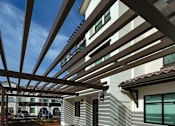 Thumbnail 9 of 61 - A modern house with a white exterior and a wooden pergola.