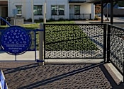 Thumbnail 3 of 61 - A blue sign with white letters is on a gate.