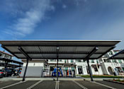 Thumbnail 11 of 61 - A parking lot with a building in the background and a blue sky above.