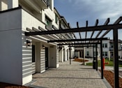 Thumbnail 7 of 61 - A modern building with a white facade and a black pergola.