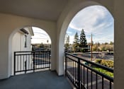 Thumbnail 53 of 61 - A balcony with a black railing and a view of a parking lot and trees.