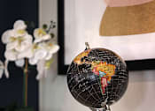 Thumbnail 60 of 61 - A black globe with a wooden stand is placed on a shelf.