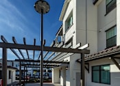 Thumbnail 57 of 61 - A modern building with a white facade and a black lamp post.