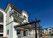 Thumbnail 50 of 61 - A white building with a black roof and a wooden pergola.
