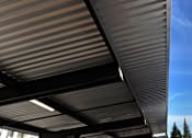 Thumbnail 41 of 61 - A corrugated metal roof with a blue sky in the background.