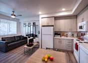 Thumbnail 48 of 61 - A modern kitchen with a black couch and a wooden table with an apple and two lemons on it.