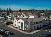 Thumbnail 23 of 61 - A large white building with a red roof is surrounded by a parking lot.