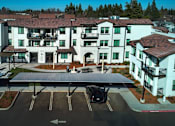 Thumbnail 18 of 61 - A large white building with a parking lot in front.