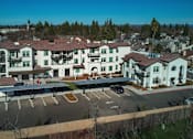 Thumbnail 25 of 61 - A large white building with a red roof is surrounded by a parking lot.
