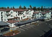 Thumbnail 27 of 61 - A large white building with a red roof and a parking lot in front.