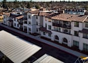 Thumbnail 14 of 61 - A large white building with a red tile roof is surrounded by a parking lot.